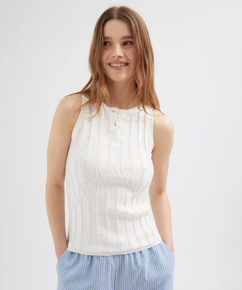 Woman wearing a white sleeveless top with a plain background