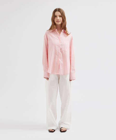 Woman wearing a pink shirt and white pants on a white background