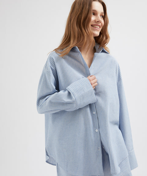 Woman wearing a light blue striped shirt against a white background