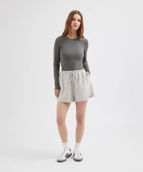 Woman wearing a gray long-sleeve top and light gray skirt on a white background
